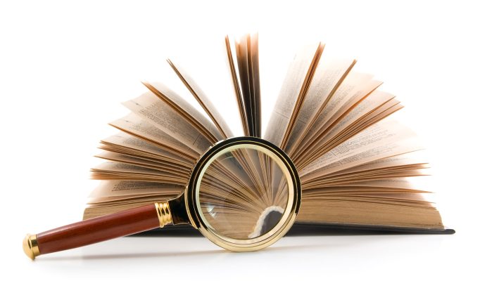 Magnifying glass and opened book, isolated on white background.