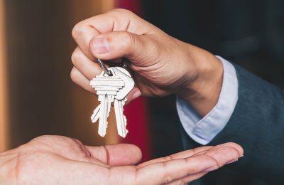 estate agent giving house keys to woman and sign agreement in office