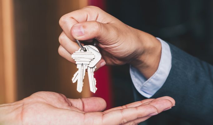 estate agent giving house keys to woman and sign agreement in office